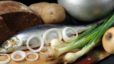 Картофель, горох, сельдь, луковые кольца, черный хлеб, доска, нож