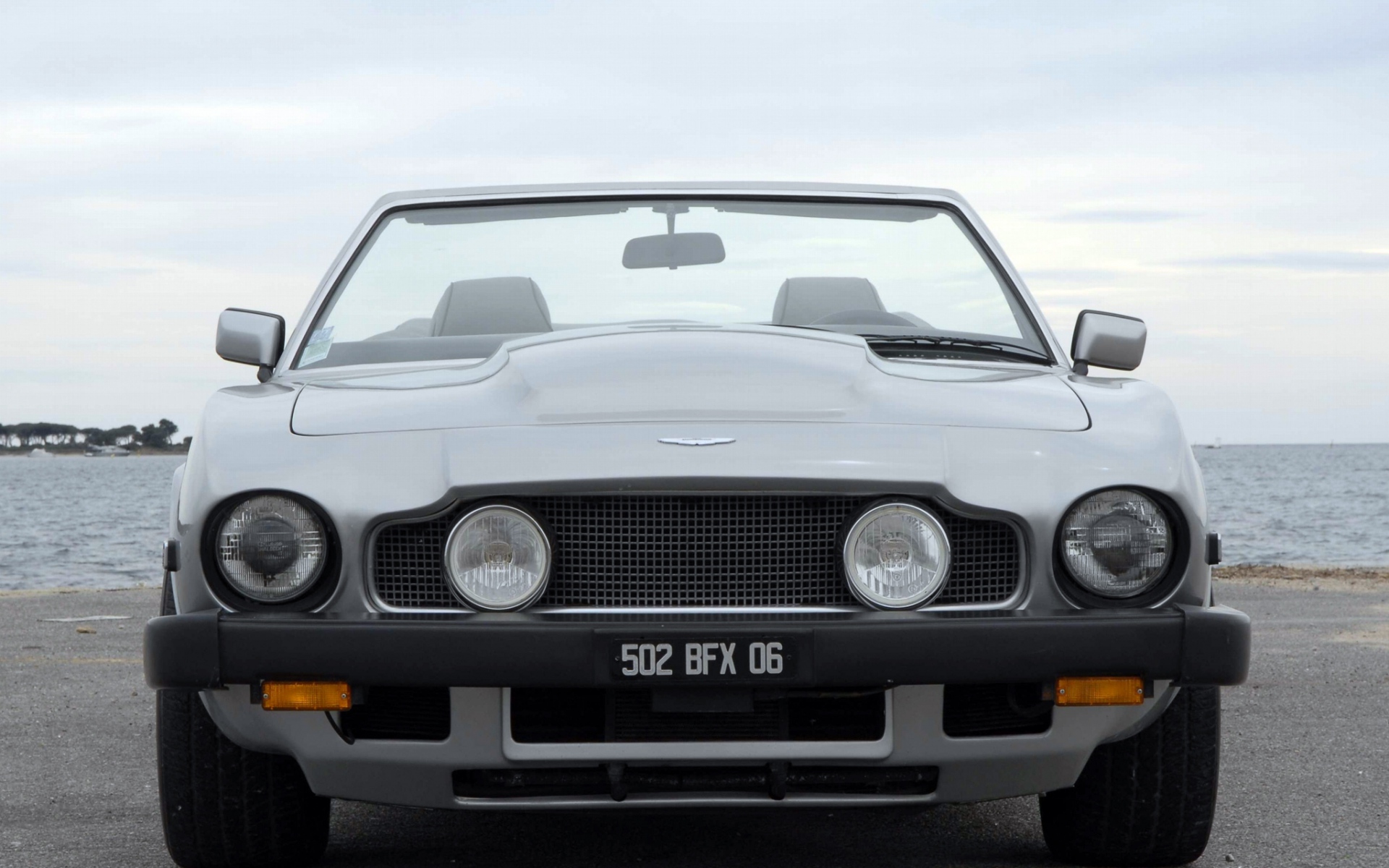 Картинки Aston martin, v8, volante, 1977, серый, вид спереди, автомобиль, море, кабриолет фото и обои на рабочий стол