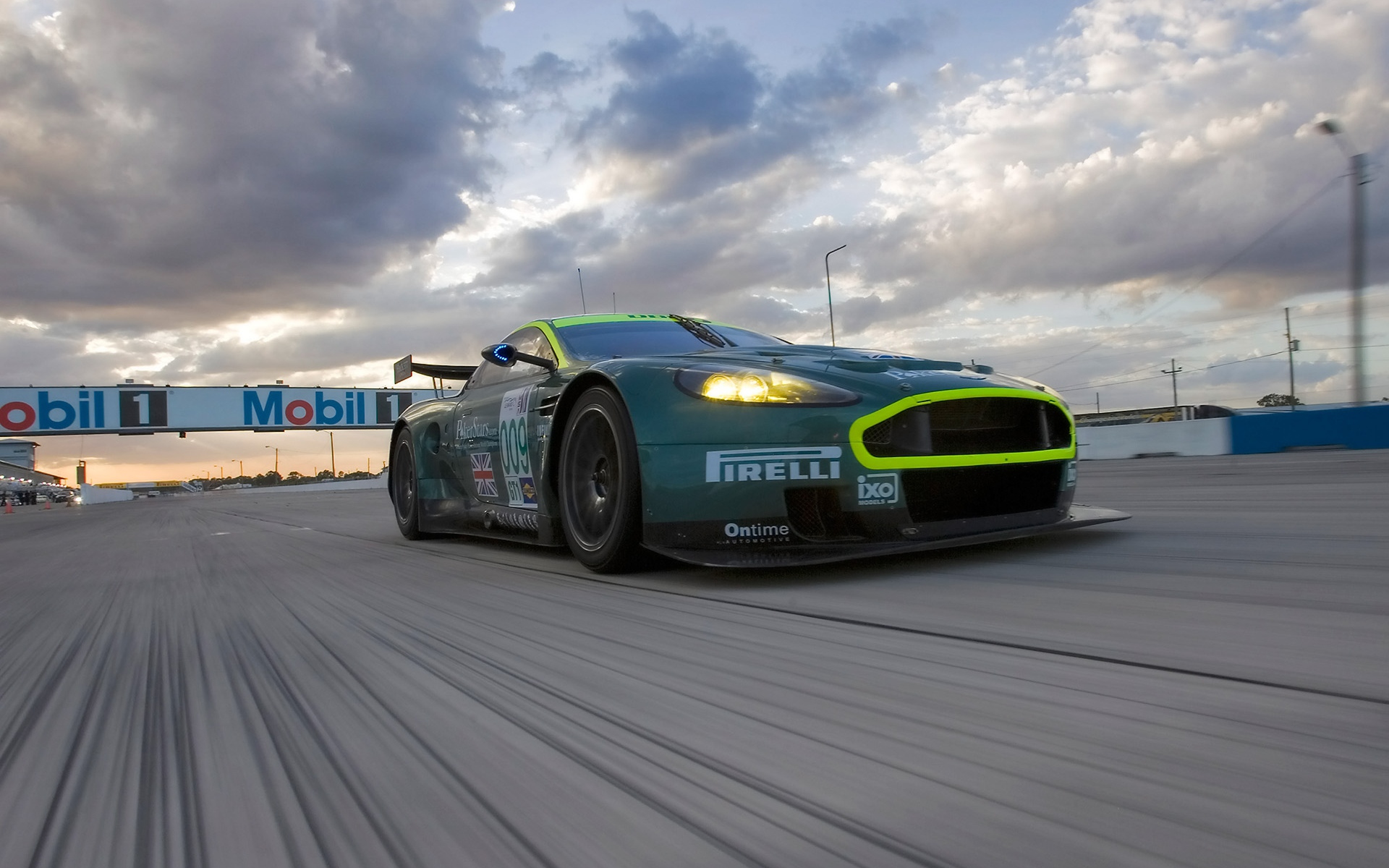 Картинки Aston martin, dbr9, 2005, зеленый, вид спереди, стиль, спорт, автомобиль, гоночный автомобиль, скорость, облака, асфальт фото и обои на рабочий стол